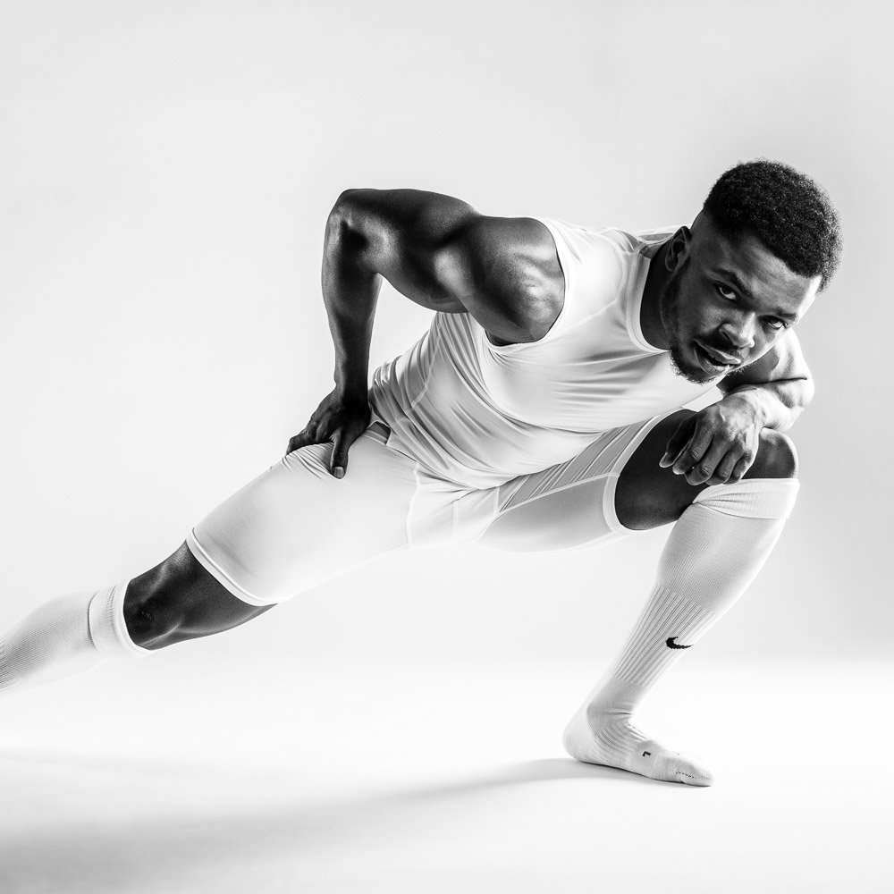 Studio-Sportportrait eines American Footballers der mit Ball auf die Kamera zu läuft